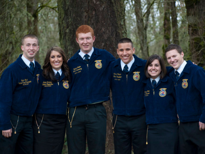 Six members of the Oregon FFA State Officer team stand together wearing blue coruroy FFA jackets.