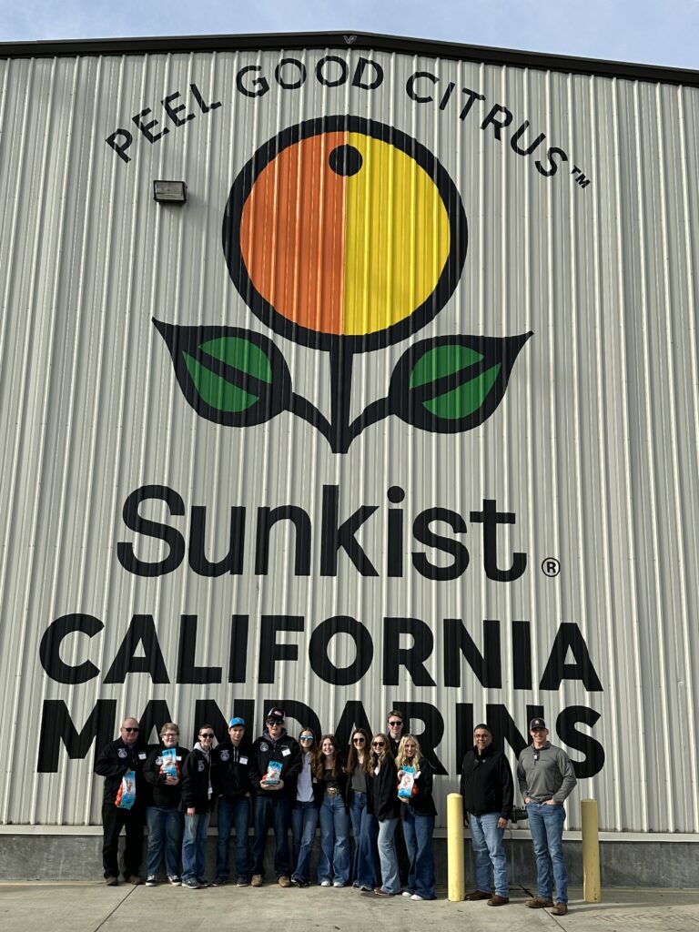 Oregon FFA members pose in front of a Sunkist California Mandarins processing facility.