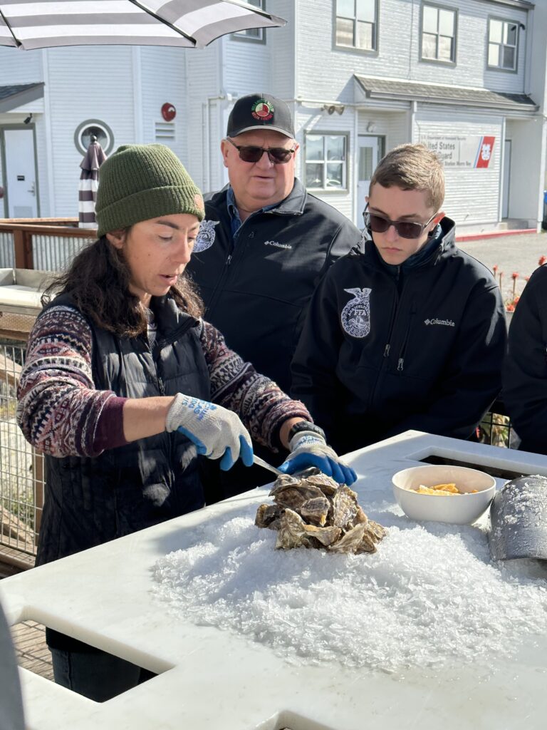 A Morro Bay Oyster Company employee teaches Oregon FFA members how to shuck an oyster.